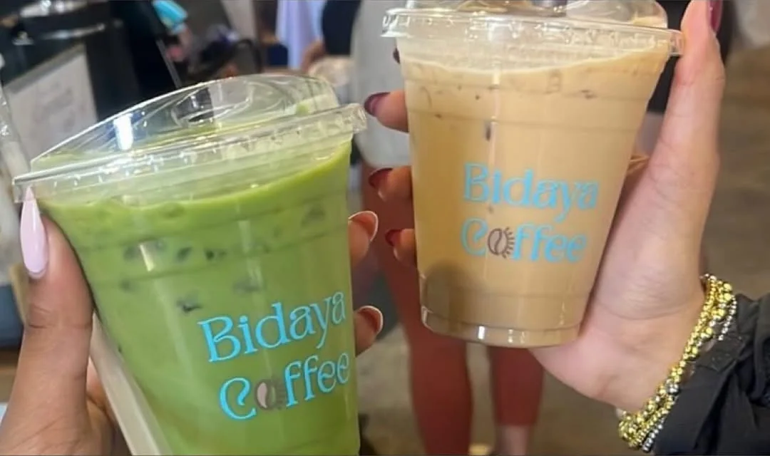 Guests holding an iced matcha and an iced latte in branded Bidaya Coffee cups